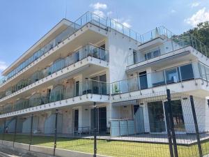 a white building with balconies and a fence at ZAWIA APARTMAN in Balatonföldvár