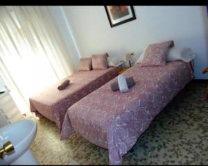 - une chambre avec 2 lits avec des draps roses et une fenêtre dans l'établissement Hostal Puerto de Santa Maria, à El Puerto de Santa María