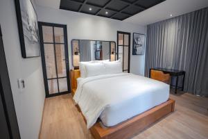 a bedroom with a large white bed and a chair at Secana Beachtown in Canggu