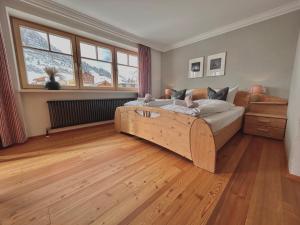 ein Schlafzimmer mit einem großen Bett und Holzboden in der Unterkunft Haus Wallis - Ski-In Ski-Out mit Frühstück am Arlberg in Warth am Arlberg