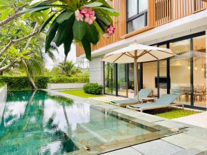 a swimming pool in front of a house with an umbrella at Moon Villa Phu Quoc - 3 Bedroom - Private pool in Phu Quoc