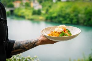 a person holding a bowl of pasta and vegetables at Penzion Šterk in Most na Soči