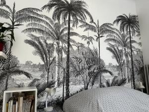 a bedroom with palm trees mural on the wall at Studios climatisés proche mer in Nice