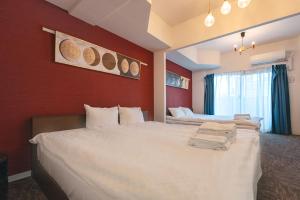 Un dormitorio con dos camas y una pared roja. en 谷町君･星Hotel･恵美須西, en Osaka
