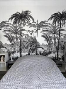 Schlafzimmer mit einem Bett mit Palmen an der Wand in der Unterkunft Studios climatisés proche mer in Nizza