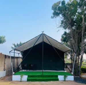 a black tent with two chairs on a green lawn at K's Villa Bella in Bhuj