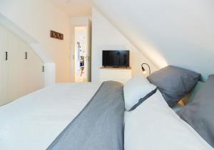 um quarto com uma cama branca e uma televisão em Paradise Suite - Penthouse mit Meerblick em Timmendorfer Strand