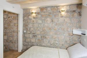 - une chambre avec un mur en pierre et un lit dans l'établissement Apartments Bottega, à Dubrovnik