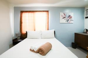 a bedroom with a bed with a towel on it at Arzo Hotel Makati in Manila