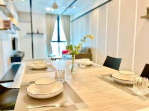 a table with plates and glasses and a vase with flowers at Comfort Place 1-8 Pax 3Q beds Ara Damansara Center in Petaling Jaya
