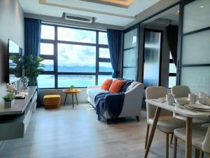 een woonkamer met een bank en een tafel met stoelen bij J'Stay Seaview Suite Jesselton Quay Kota Kinabalu in Kota Kinabalu