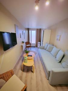 a living room with a white couch and a table at Studio 1 piece vacances proche de la mer in Le Grau-du-Roi +3 photos