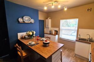 une cuisine avec une table en bois et un mur bleu dans l'établissement Potter's Retreat by Spires Accommodation an adorably quirky place to stay in Stoke on Trent, à Longport