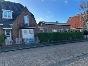 a brick house with a fence on a street at Riposo in West-Terschelling