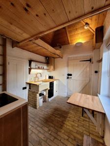 a large kitchen with wooden ceilings and a wooden table at The Lookout: Cosy Compact Cottage in Totland