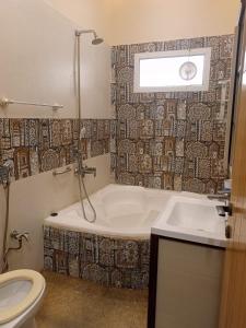 a bathroom with a tub and a toilet and a sink at White Lotus Karachi in Karachi