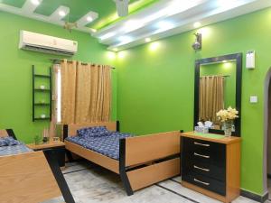a green room with two beds and a mirror at White Lotus Karachi in Karachi