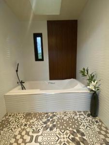 a bath tub in a bathroom with a vase of flowers at Jill’s Maison in Bataan