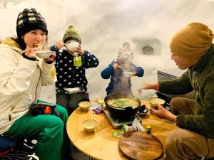 Un groupe de personnes assises autour d'une table et mangeant de la nourriture dans l'établissement Labo Land Kurohime "rental cottage cottage" - Vacation STAY 62616v, à Shinano