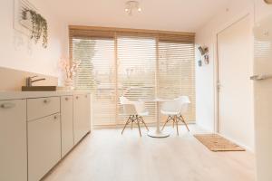 a kitchen with a table and two white chairs at Studio Loet in Schagen