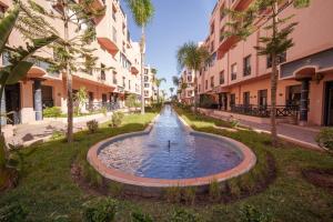 uma fonte no meio de uma rua com edifícios em Appartement aux portes de la palmeraie em Marraquexe