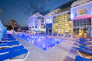 a pool at a hotel with blue chairs and buildings at Sealife Family Resort Hotel in Antalya