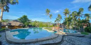- une piscine dans un complexe avec des palmiers dans l'établissement Casa Basilisa Eco-Boutique Resort by Cocotel, à Guinobatan