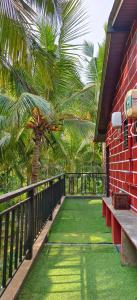 balcón con césped verde y palmera en Walawal Bliss Farm Stay, en Vālāval
