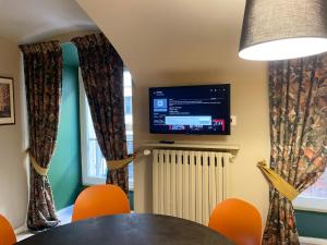 een eetkamer met een tafel, stoelen en een televisie bij Obelisque 1850 con posto auto! in Turijn