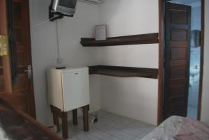 a room with a refrigerator and a tv on a wall at Casa de Dona Rosa in Mata de Sao Joao