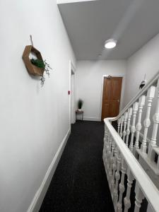 a hallway with white walls and stairs with a plant on the wall at Serendipity By Habitat101 in Middlesbrough