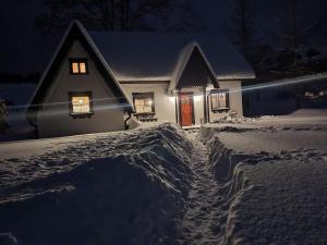a house covered in snow at night at Szczęśliwy Domek in Wetlina