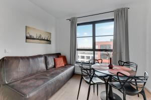 a living room with a leather couch and a table at DOKI Living & Foodhall Apartament in Gdańsk