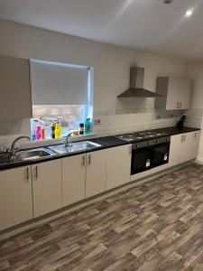 cocina con armarios blancos, fregadero y ventana en Serendipity By Habitat101, en Middlesbrough