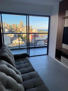 a living room with a couch in front of a large window at Studio 1quarto Vista Mar Barra Business & Travel in Salvador