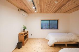 1 dormitorio con cama y techo de madera en プラベート薪サウナ付 1日1組限定ease1高山村, en Takayama