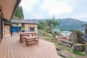 een houten terras met een bank bovenop een huis bij プラベート薪サウナ付 1日1組限定ease1高山村 in Takayama