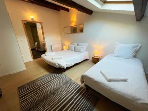 two beds in a room with two lamps and a rug at Spacieux 5 pers Centre+Terrasse in Clermont-Ferrand