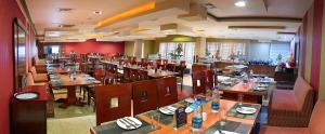 a restaurant with wooden tables and chairs and a large room at MGM Mark Whitefield in Bangalore