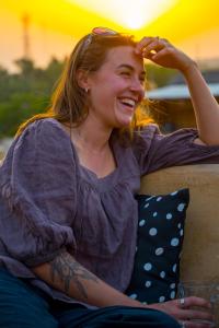 a woman sitting on a bench with a smile at Open Road Hostel and Cafe in Jaisalmer