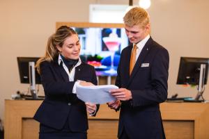 Ein Mann und eine Frau in Anzügen, die eine Zeitung ansehen. in der Unterkunft Teaching Hotel in Maastricht