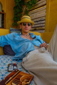 un homme portant un chapeau posé sur un lit dans l'établissement Open Road Hostel and Cafe, à Jaisalmer