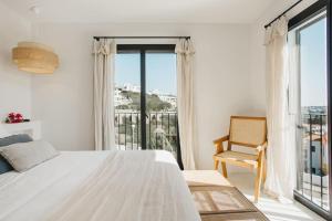 a white bedroom with a bed and a balcony at Villa Alma luxe & sea views in Cala Llonga