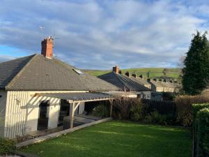 a white house with a roof and a yard at Pass the Keys The Cabin Stylish and Elegant for 4 and Furry Friends in Hayfield