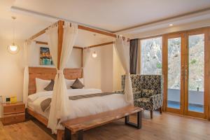 a bedroom with a canopy bed and a chair at Echor Palm Bliss Riverside Resort & Spa Kasol in Kasol