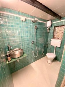 a green tiled bathroom with a shower and a toilet at Bandra Cottage (With Yard) in Mumbai