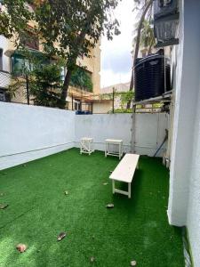 een patio met een bank op een groene vloer bij Bandra Cottage (With Yard) in Mumbai