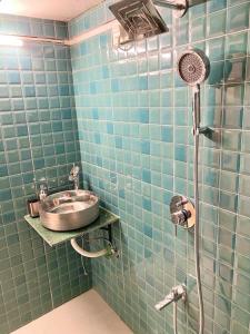 a blue tiled bathroom with a sink and a shower at Bandra Cottage (With Yard) in Mumbai