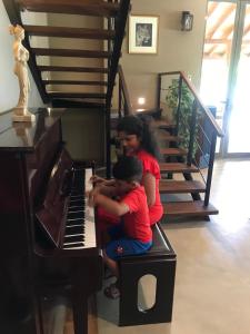 a woman and a child sitting on a piano at Allure Yala Luxury Suites by Allure Leisure in Yala