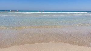 una spiaggia con persone nell'oceano e nell'acqua di Trulli Aurasia a Ostuni